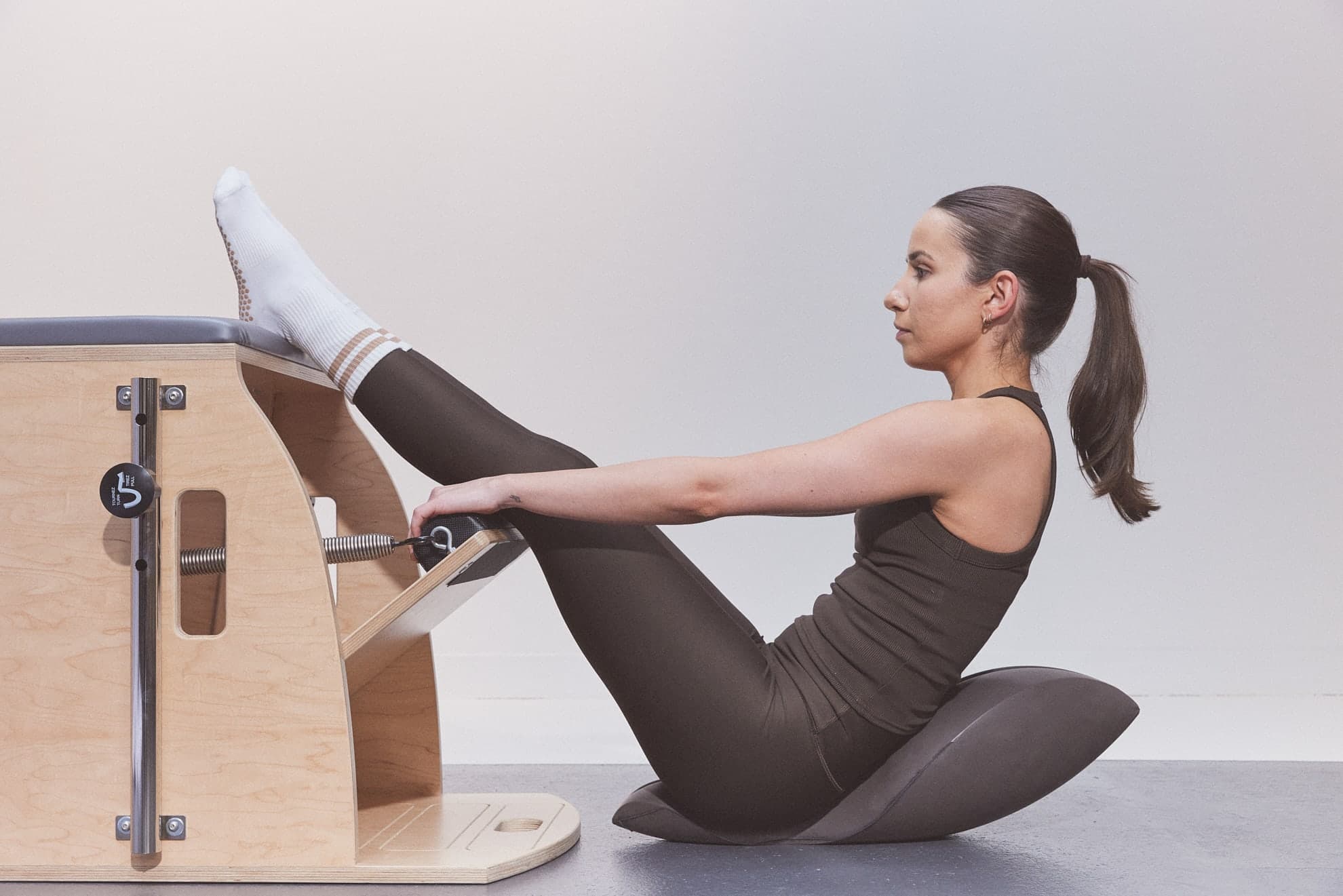 Une cliente assise sur un Oov, tenant la pédale de la Wunda Chair avec un pied appuyé sur la chaise